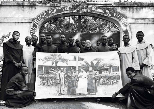 Nowicjusze i profesi z klasztoru w Bangi dziś ze zdjęciem z początków misji