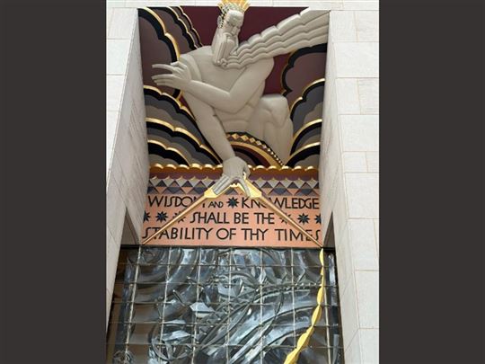 Płaskorzeźba i napis nad głównym wejściem do „The Rockefeller Centre”: „Mądrość i wiedza będą podstawą stabilności twoich czasów''